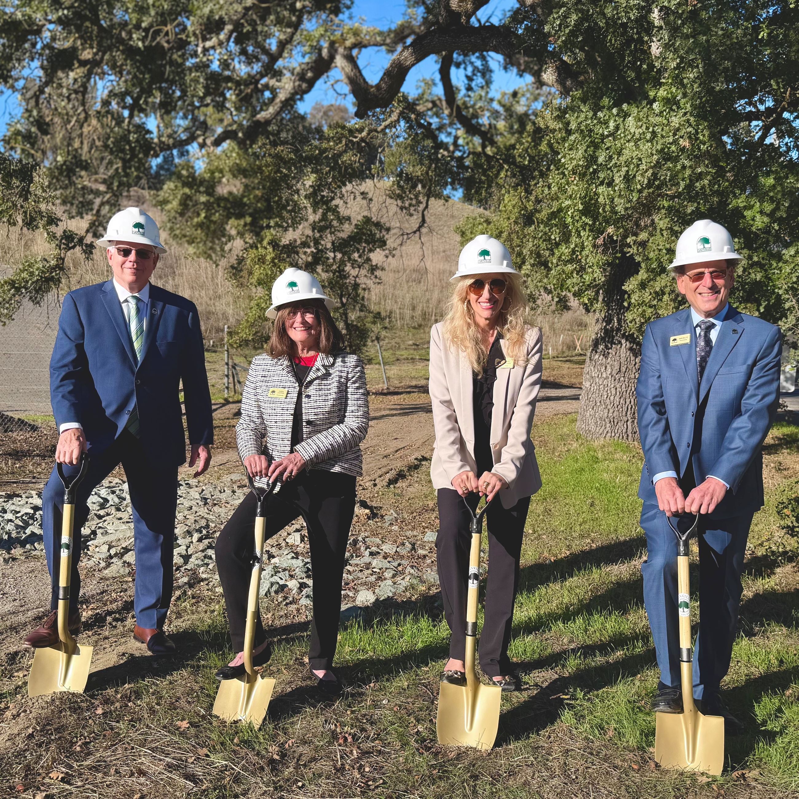 councilmembers with shovels and wearing hard hats at a trail
